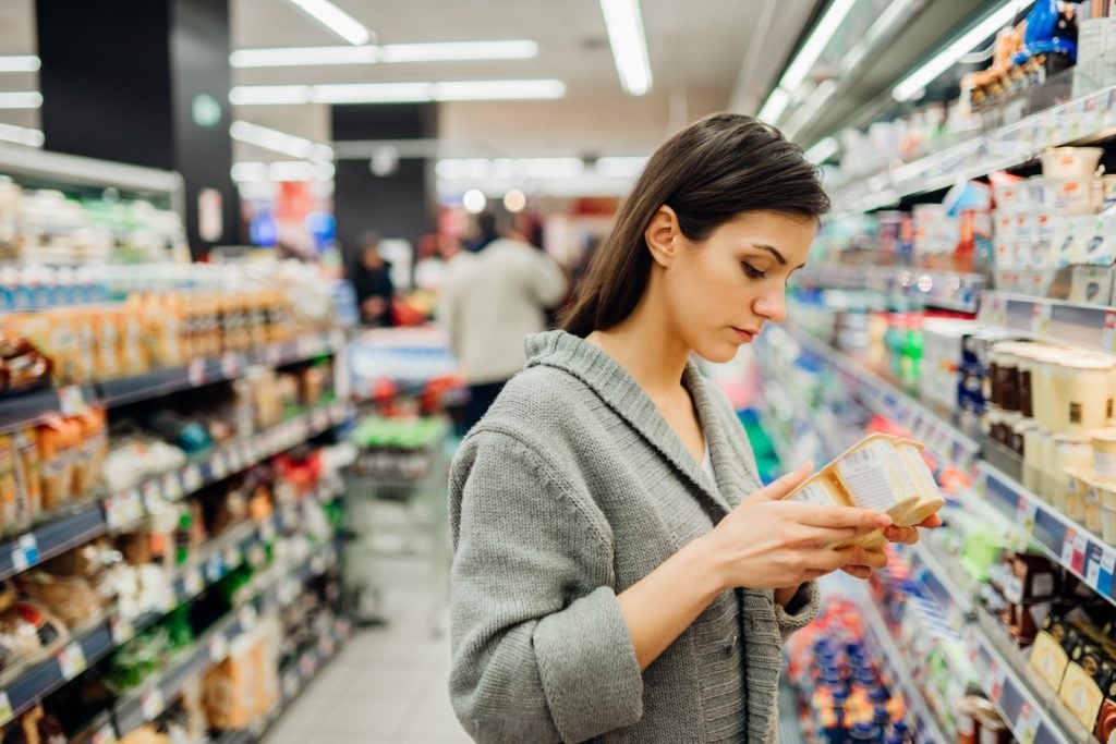 Low FODMAP diet: A woman reads the ingredients on a package of yogurt