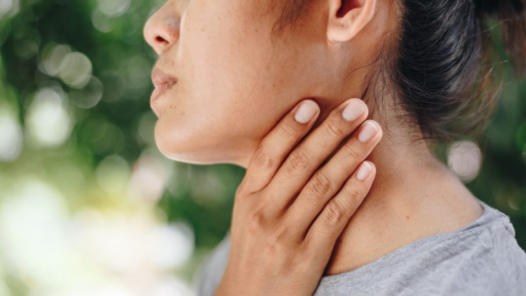 Pain in thyroid: A woman holds her neck