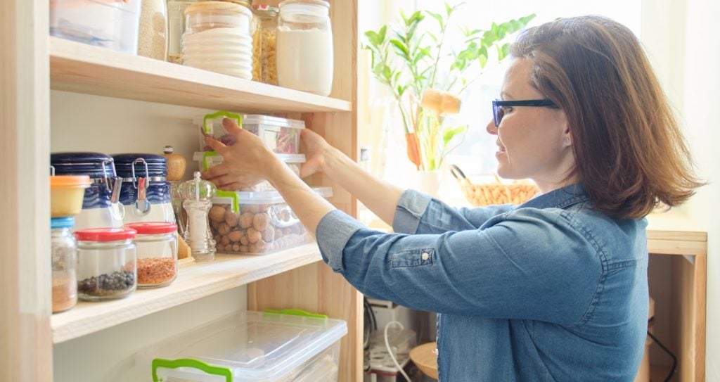 woman taking kitchenware and food from the shelves