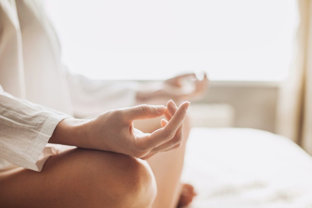 ibs treatment: girl meditating in bed