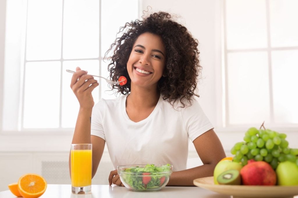 symptoms of IBS attack: Woman smiling while eating a salad