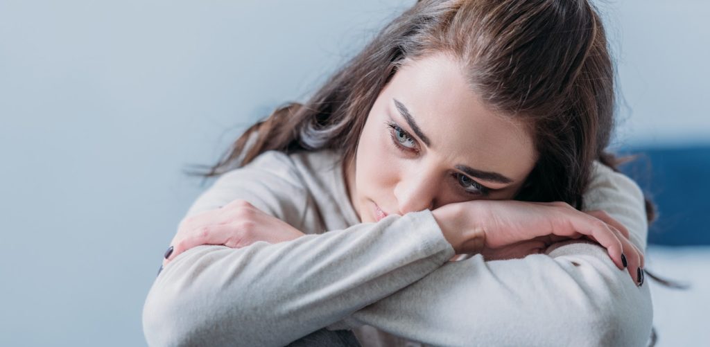 symptoms of IBS attack: Woman resting her head on her arms