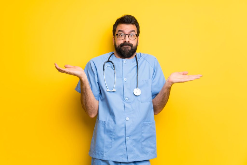 brain fog: Shrugging doctor wearing scrubs against a yellow background
