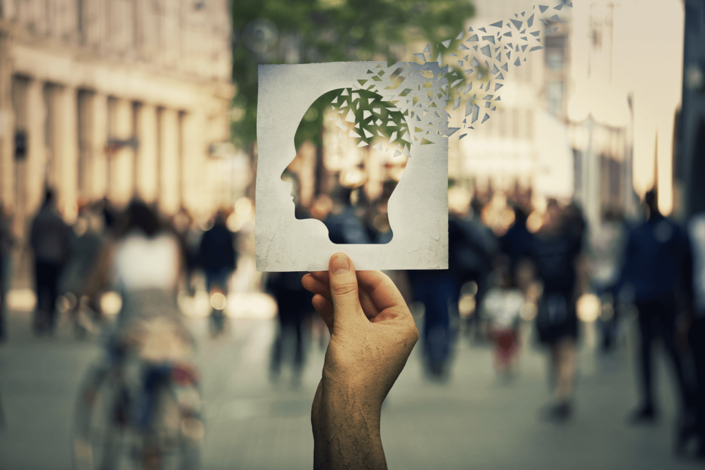 memory training: Person holding a paper cutout with the shape of a human head with pieces of it fading away
