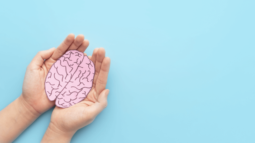 early signs of dementia checklist: Person holding a human brain shape made of paper against a light blue background