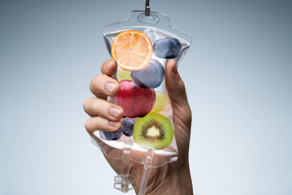 IV vitamin therapy: person holding a saline back with fruits inside