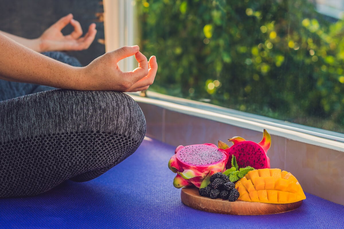 Person meditating beside a plate of fruits