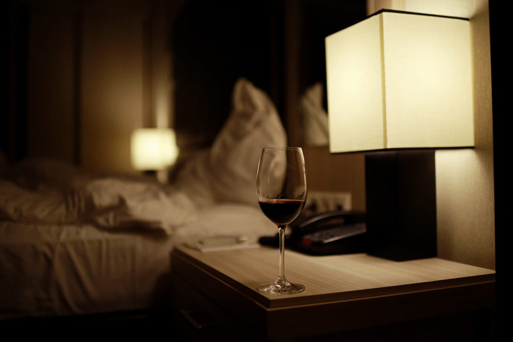 Melatonin and alcohol: glass of wine on a bedside table