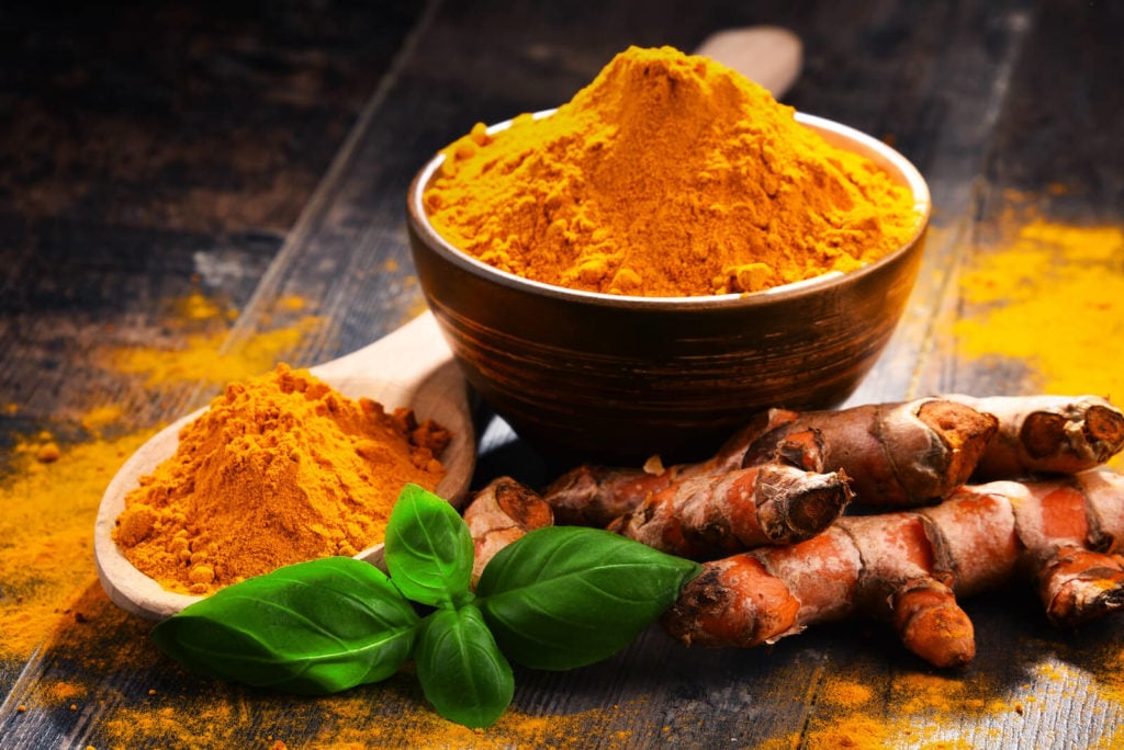 Natural remedies for rheumatoid arthritis: bowl and a spoonful of turmeric powder