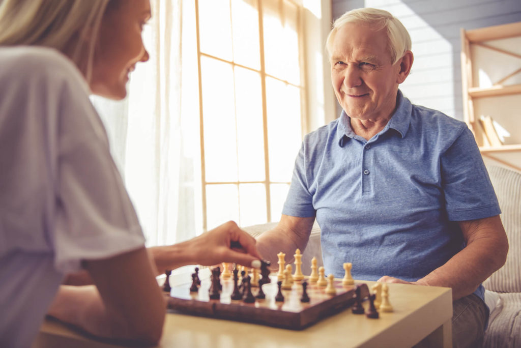 Young woman playing chess with an elderly man
