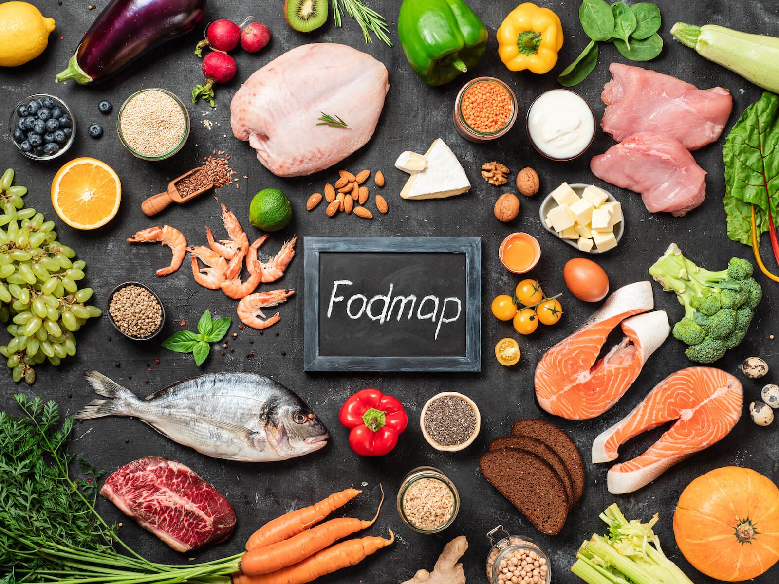 Stomach distension: Fodmap written in chalk surrounded by various fresh ingredients