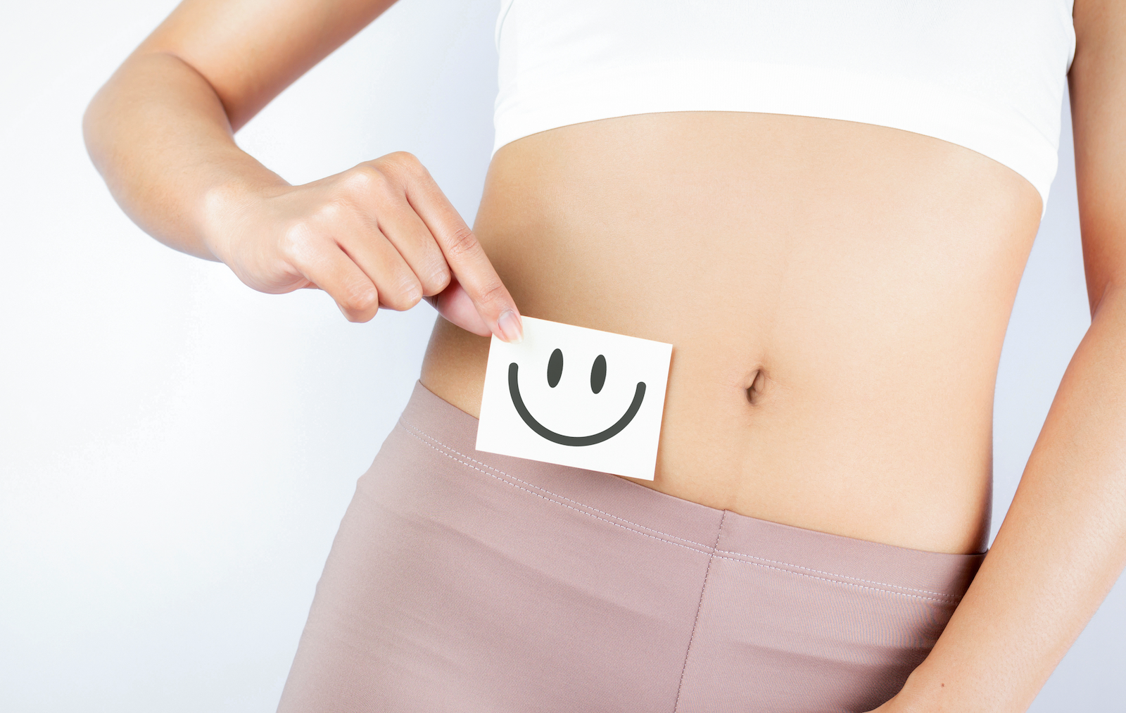 Woman holding a piece of paper with a smiley face against her stomach