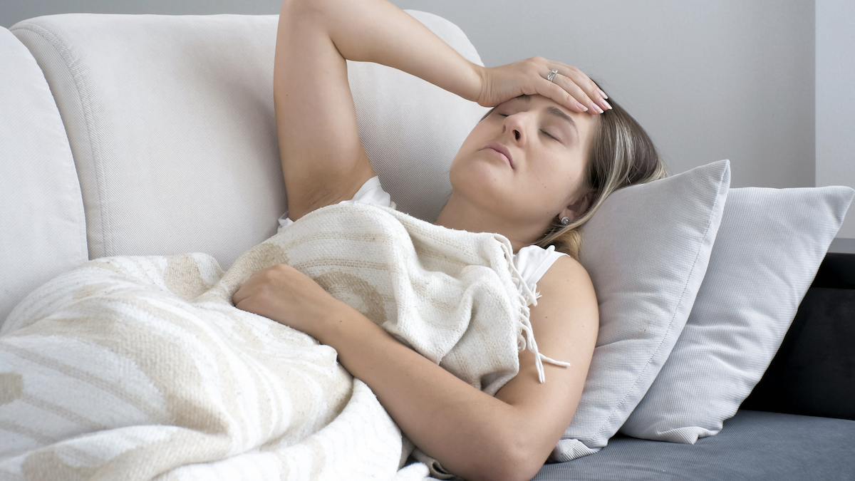 Antimicrobial vs antibacterial: Woman with a headache lying on the couch